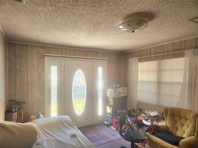 carpeted entryway with a textured ceiling and wood walls
