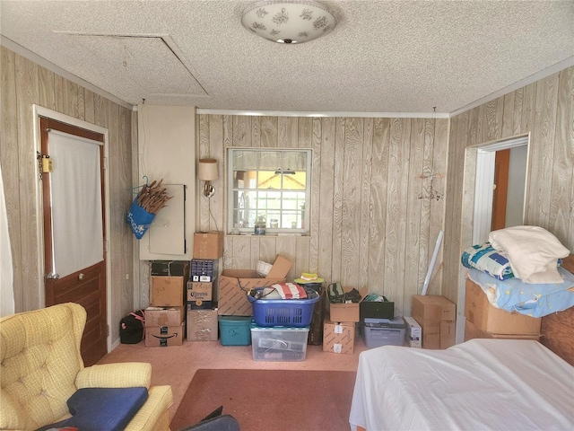 bedroom featuring a textured ceiling, attic access, and wooden walls