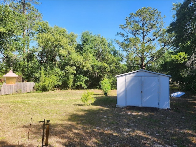 view of yard featuring a storage shed, fence, and an outdoor structure