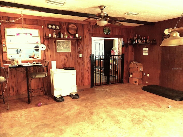 living room with ceiling fan, wood walls, visible vents, and concrete floors