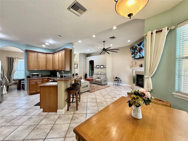 30554 Quince Ave, Eustis, FL 32736 - kitchen with arched walkways, open floor plan, a breakfast bar area, light tile patterned floors, and a peninsula