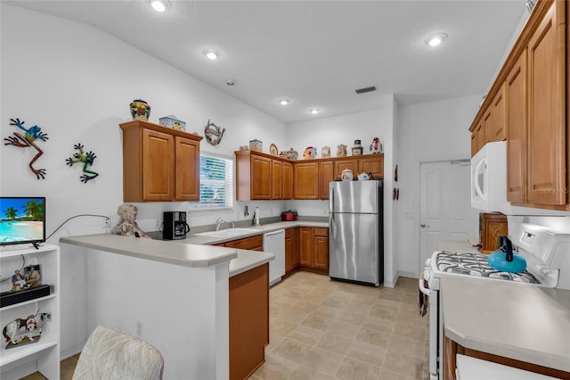 kitchen featuring a sink, brown cabinetry, white appliances, light countertops, and a peninsula