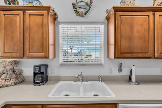 kitchen with brown cabinetry, dishwasher, a sink, and light countertops