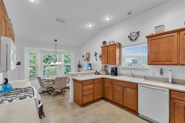 kitchen featuring vaulted ceiling, a sink, white appliances, a peninsula, and visible vents