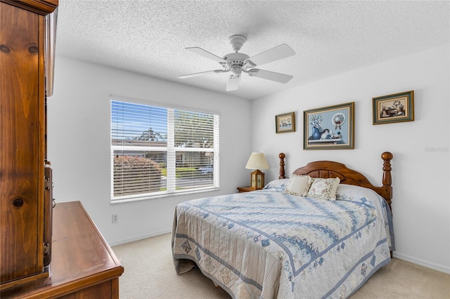 bedroom featuring light colored carpet, baseboards, a ceiling fan, and a textured ceiling