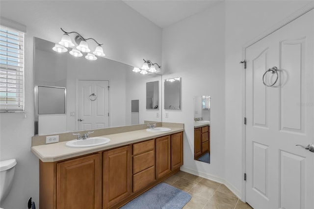 bathroom with tile patterned floors, a sink, double vanity, and toilet