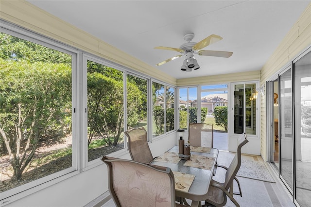 sunroom / solarium with outdoor dining area and ceiling fan