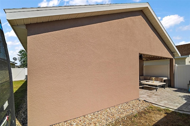 view of property exterior with fence, stucco siding, and a patio area