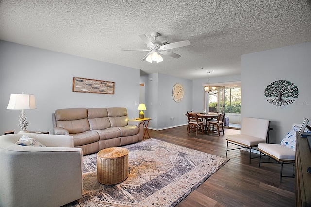 living area featuring baseboards, dark wood-style flooring, a textured ceiling, and ceiling fan with notable chandelier