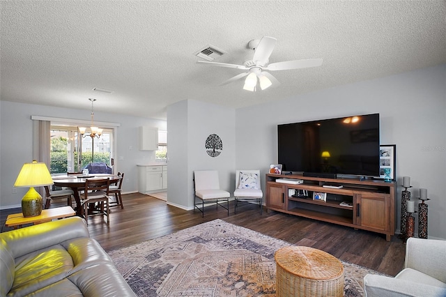 living room with wood finished floors, visible vents, baseboards, a textured ceiling, and ceiling fan with notable chandelier