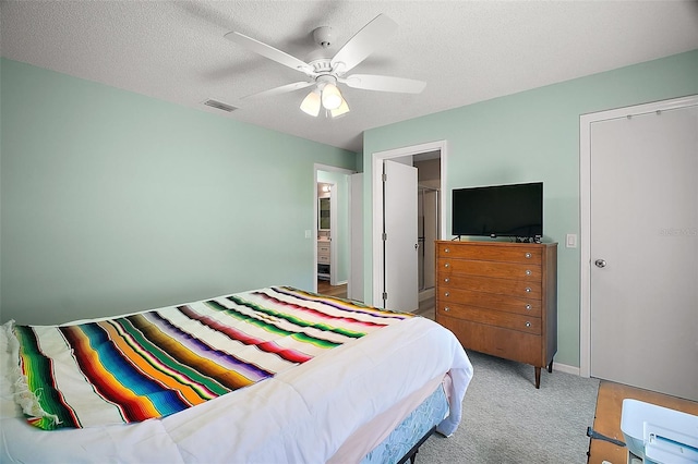 carpeted bedroom featuring a ceiling fan, visible vents, and a textured ceiling