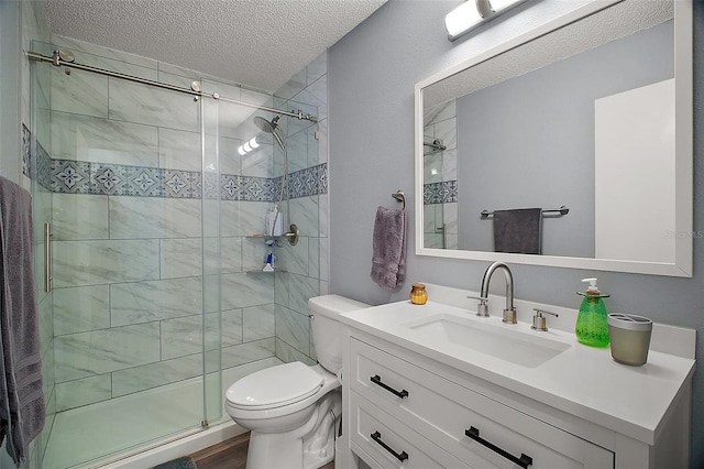 full bath featuring a shower stall, a textured ceiling, toilet, and vanity