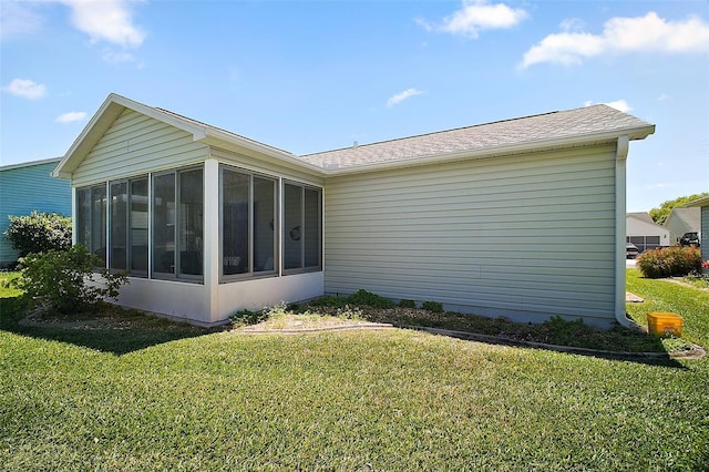 back of property with a yard, a sunroom, and a shingled roof