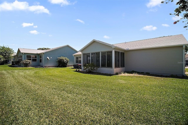 rear view of property with roof with shingles, a sunroom, and a yard