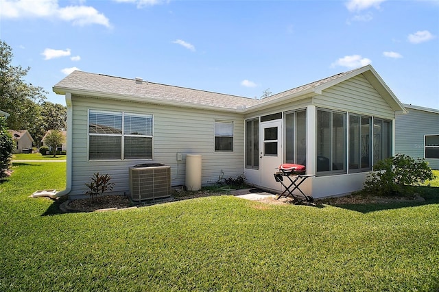 rear view of property featuring a shingled roof, a sunroom, a yard, and cooling unit