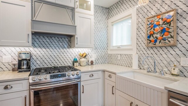 908 N Tremain St, Mount Dora, FL 32757 - kitchen featuring gas range, white cabinets, custom range hood, a sink, and backsplash