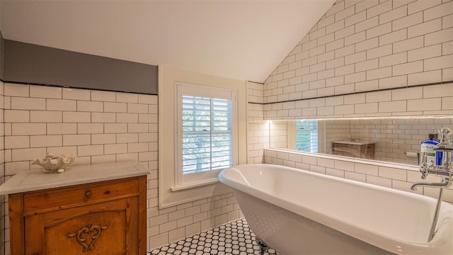 908 N Tremain St, Mount Dora, FL 32757 - full bathroom featuring tile walls, tile patterned floors, vaulted ceiling, and a freestanding bath