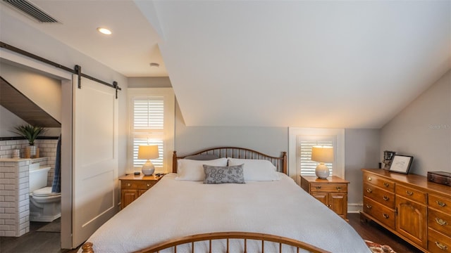 908 N Tremain St, Mount Dora, FL 32757 - bedroom with visible vents, lofted ceiling, ensuite bathroom, dark wood-type flooring, and a barn door