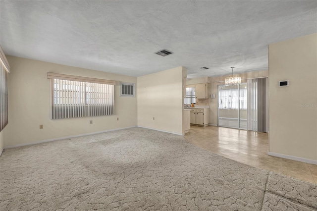 unfurnished living room featuring baseboards, a chandelier, and visible vents