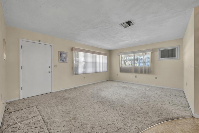 unfurnished living room with carpet, visible vents, and baseboards