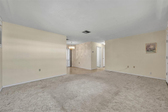 spare room with light carpet, baseboards, a notable chandelier, and visible vents