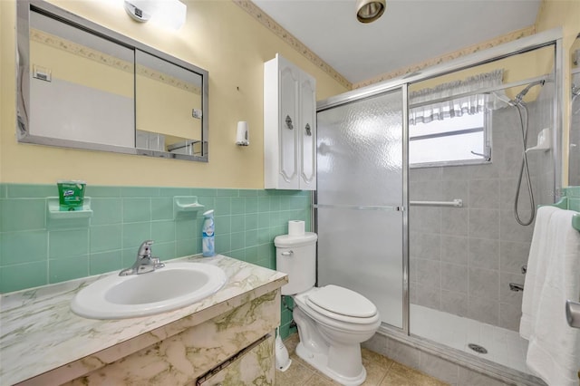 full bathroom with tile patterned floors, toilet, vanity, tile walls, and a stall shower