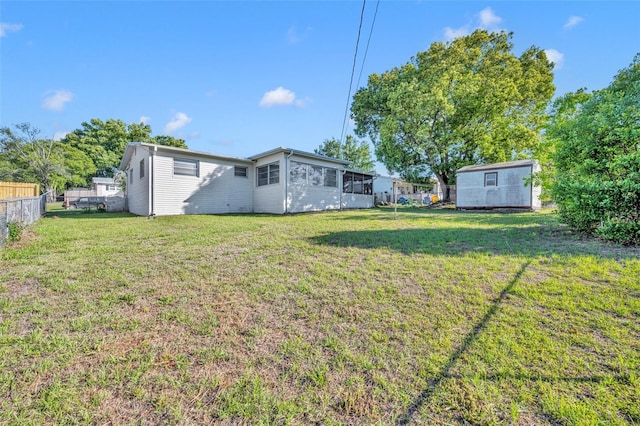 view of yard with fence, an outbuilding, a sunroom, and a storage shed