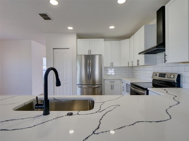 kitchen featuring wall chimney exhaust hood, a sink, visible vents, recessed lighting, and appliances with stainless steel finishes