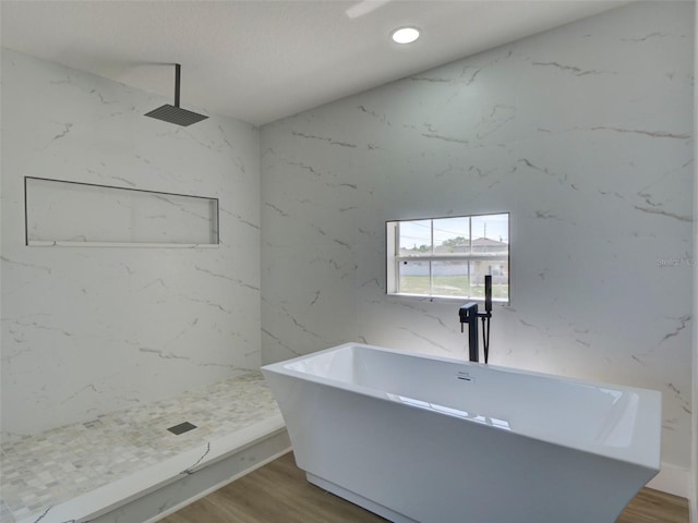interior space with a freestanding tub, wood finished floors, a marble finish shower, and recessed lighting