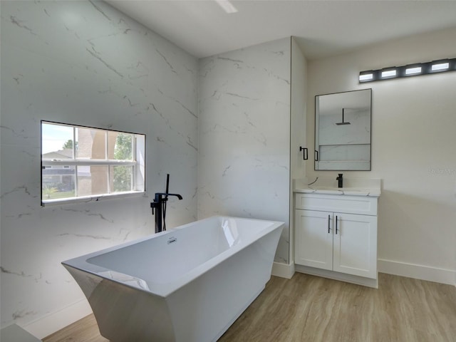 bathroom with baseboards, a freestanding tub, vanity, and wood finished floors