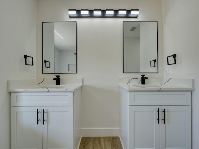full bathroom featuring baseboards, visible vents, two vanities, and a sink