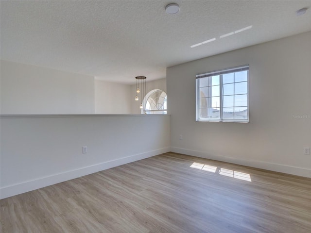 spare room featuring wood finished floors, a textured ceiling, and baseboards