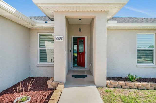 property entrance with roof with shingles and stucco siding