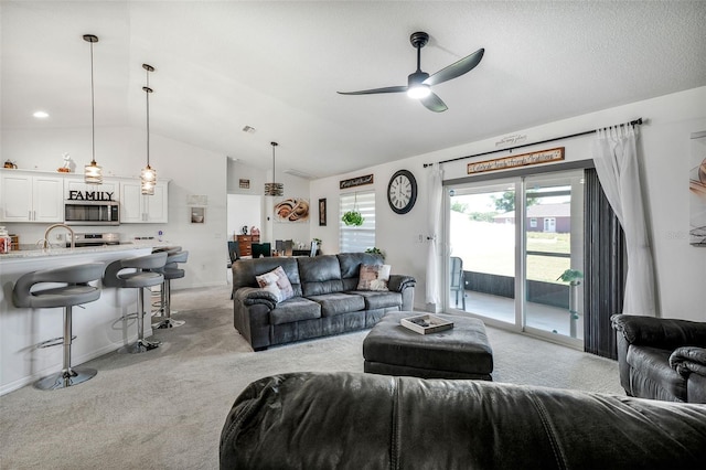 living area with light colored carpet, vaulted ceiling, a ceiling fan, and visible vents