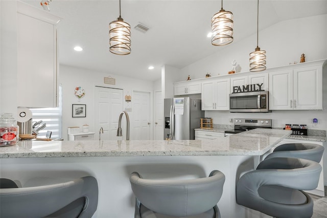kitchen featuring lofted ceiling, visible vents, appliances with stainless steel finishes, a breakfast bar area, and white cabinetry
