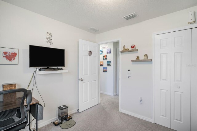 interior space featuring light colored carpet, baseboards, a textured ceiling, and visible vents