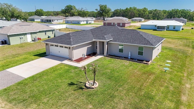 ranch-style house featuring a residential view, driveway, an attached garage, a front yard, and stucco siding
