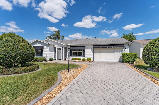 ranch-style house with an attached garage, decorative driveway, and a front lawn