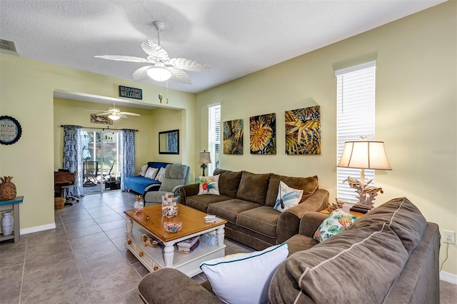 living area with ceiling fan, baseboards, and a textured ceiling