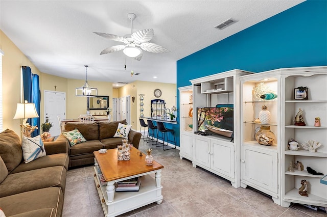 living area with ceiling fan, light tile patterned flooring, and a textured ceiling