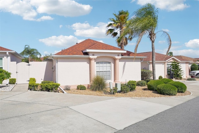 732 Ramirez Ave, The Villages, FL 32159 - view of front of home with a gate, stucco siding, and a shingled roof