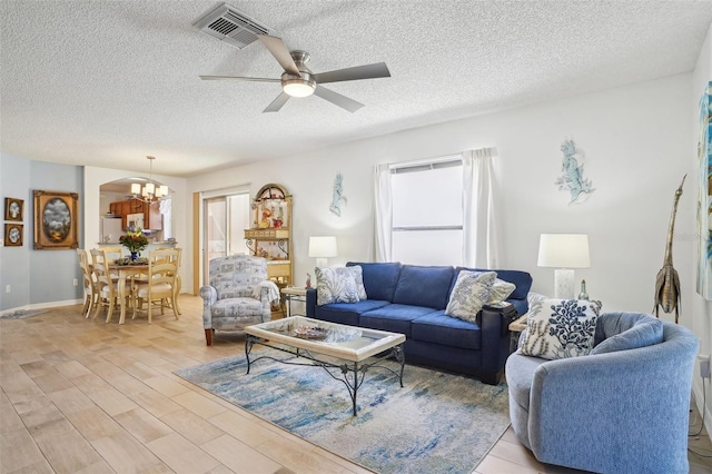 732 Ramirez Ave, The Villages, FL 32159 - living room featuring a textured ceiling, visible vents, light wood-style flooring, and ceiling fan with notable chandelier