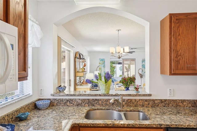 732 Ramirez Ave, The Villages, FL 32159 - kitchen with an inviting chandelier, a sink, stone counters, and arched walkways