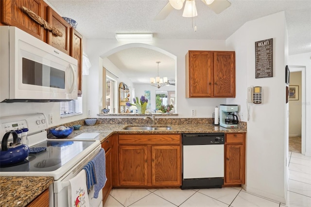 732 Ramirez Ave, The Villages, FL 32159 - kitchen with brown cabinetry, a textured ceiling, arched walkways, a sink, and white appliances