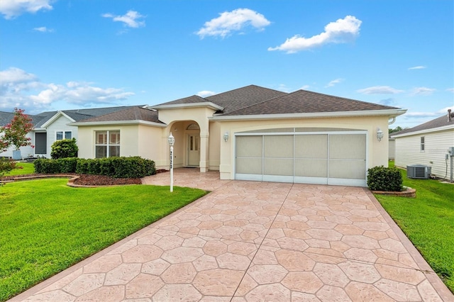 2120 Callaway Dr, The Villages, FL 32162 - view of front facade with stucco siding, a garage, driveway, central AC, and a front lawn