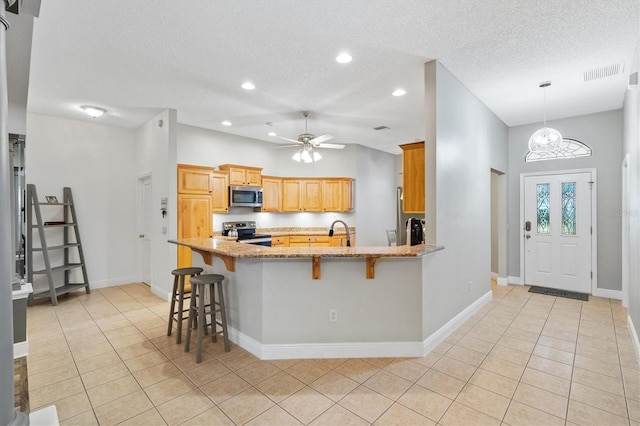 2120 Callaway Dr, The Villages, FL 32162 - kitchen featuring a peninsula, appliances with stainless steel finishes, visible vents, a textured ceiling, and light tile patterned flooring