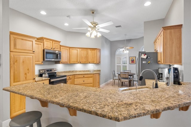 2120 Callaway Dr, The Villages, FL 32162 - kitchen featuring a sink, stainless steel appliances, ceiling fan, a breakfast bar, and a peninsula