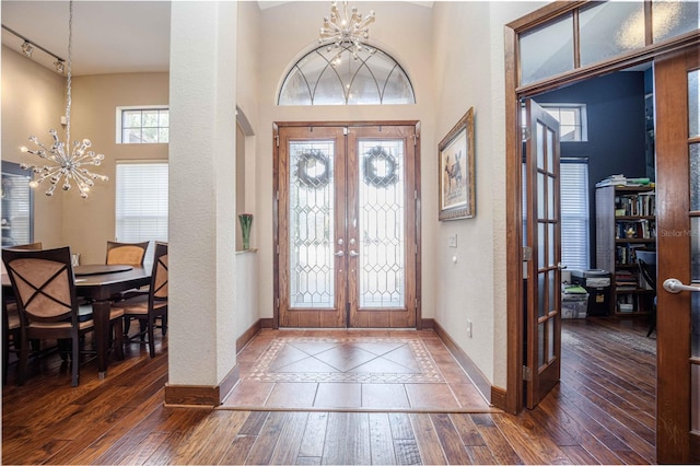 entrance foyer with baseboards, a notable chandelier, and french doors