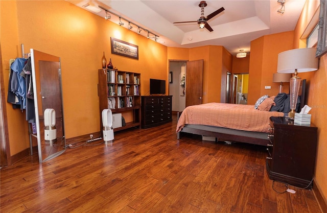 bedroom with baseboards, a tray ceiling, and wood finished floors
