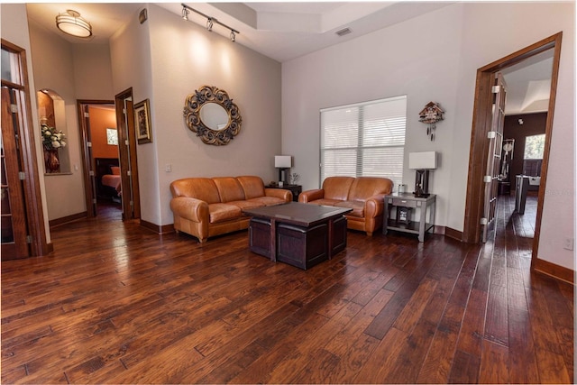 living room with arched walkways, baseboards, a high ceiling, dark wood-type flooring, and visible vents